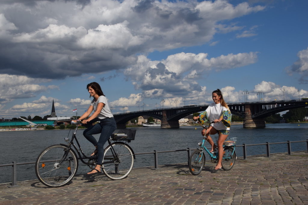 Zwei Freundinnen auf dem Fahrrad am Rhein in Mainz